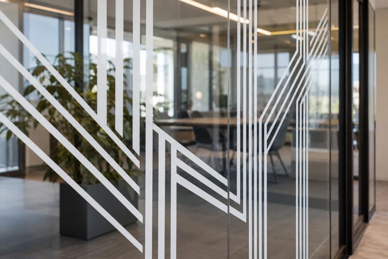 Ofis cam bölmesinde beyaz kesim folyodan uygulanmış çapraz ve dikey geometrik çizgiler