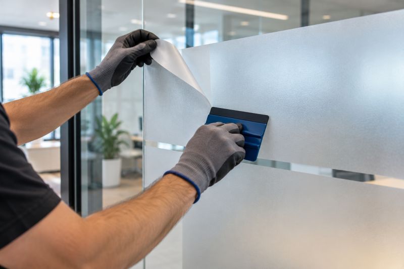 Eldivenli ellerin ofis camına saten buzlu folyoyu raketle yapıştırması